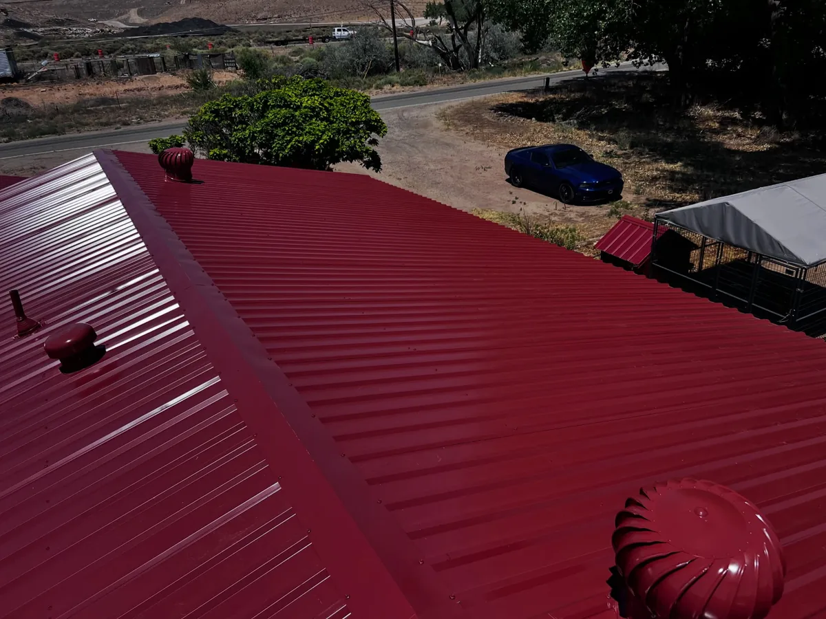 Red metal roof ridge cap with a turbine vent close to the edge